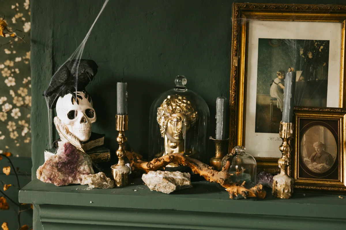 A decorative skull and raven arranged in a dark still life