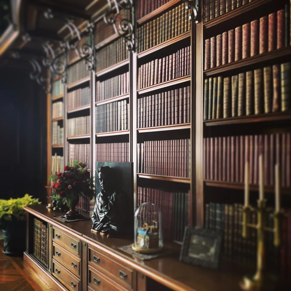 A candlelit library with dark wood and collected books